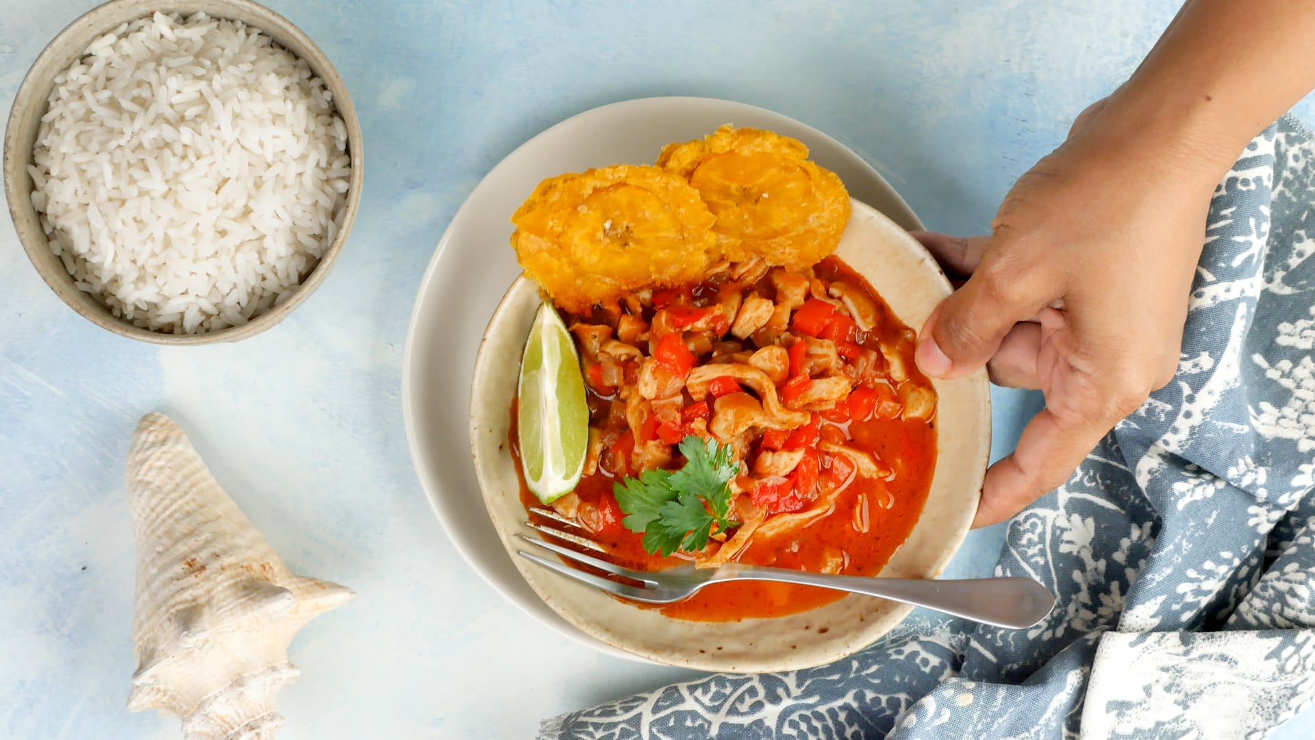 Hand holding plate lambi (conch) with rice on the side