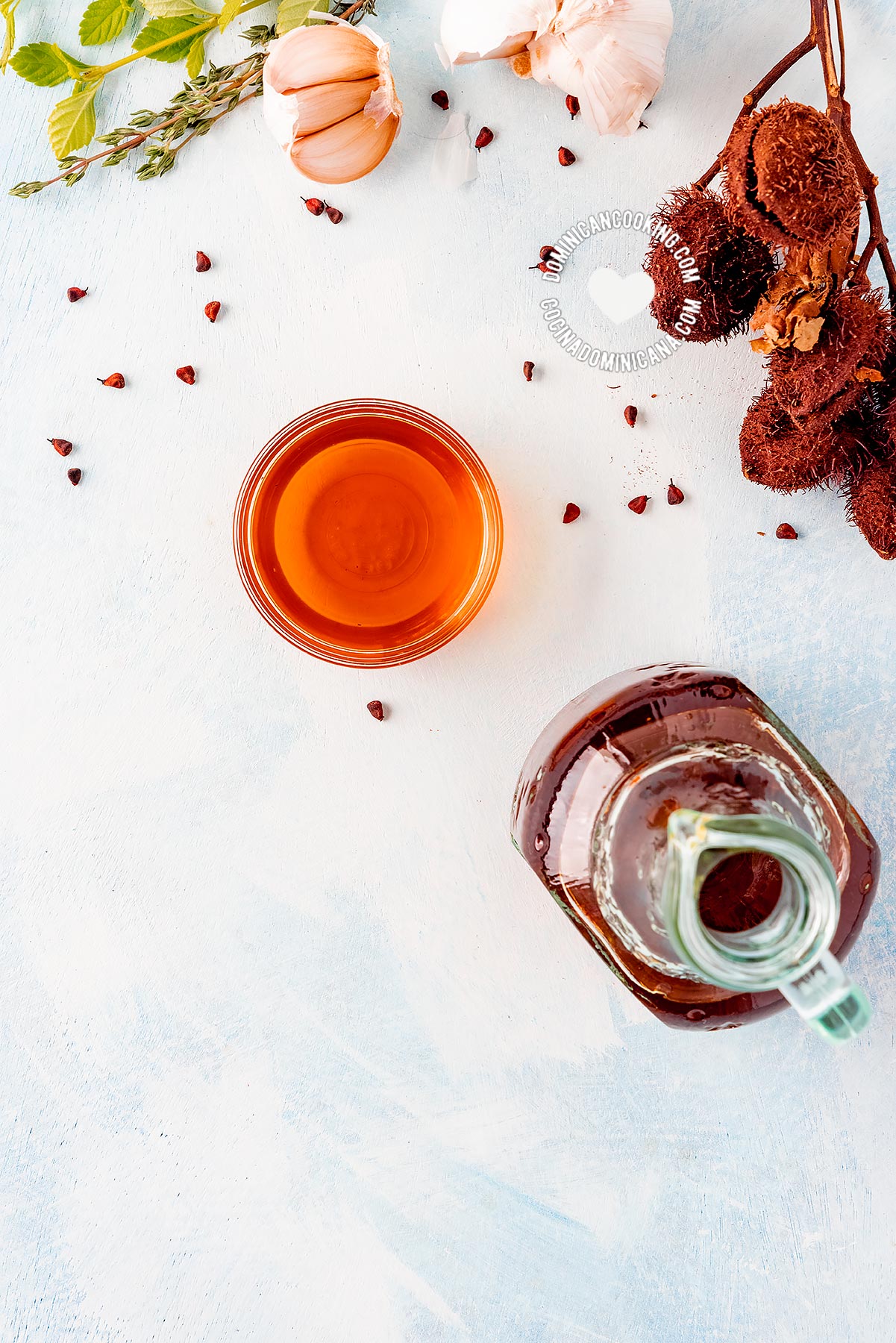 Bottle and bowl of aceite de bija (annato oil) and ingredients