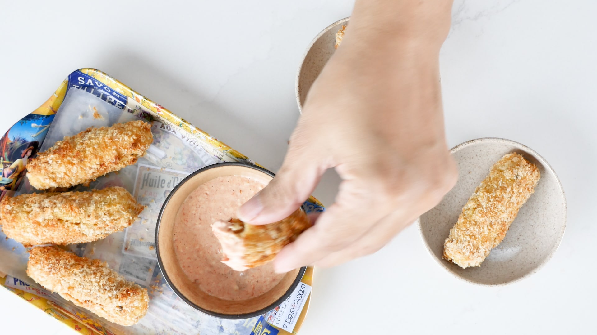 Dipping potato croquettes in pink sauce