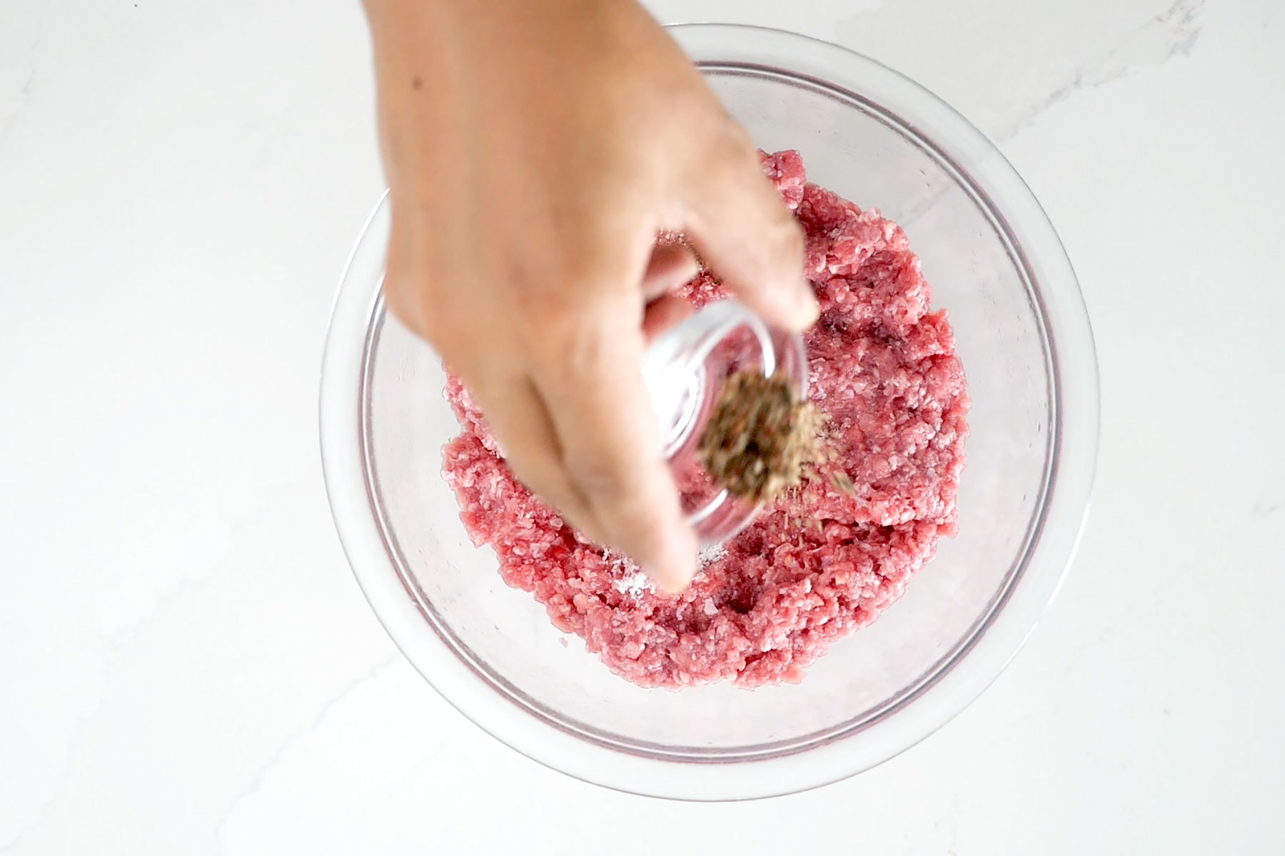 Hand sprinkling minced meat with pepper