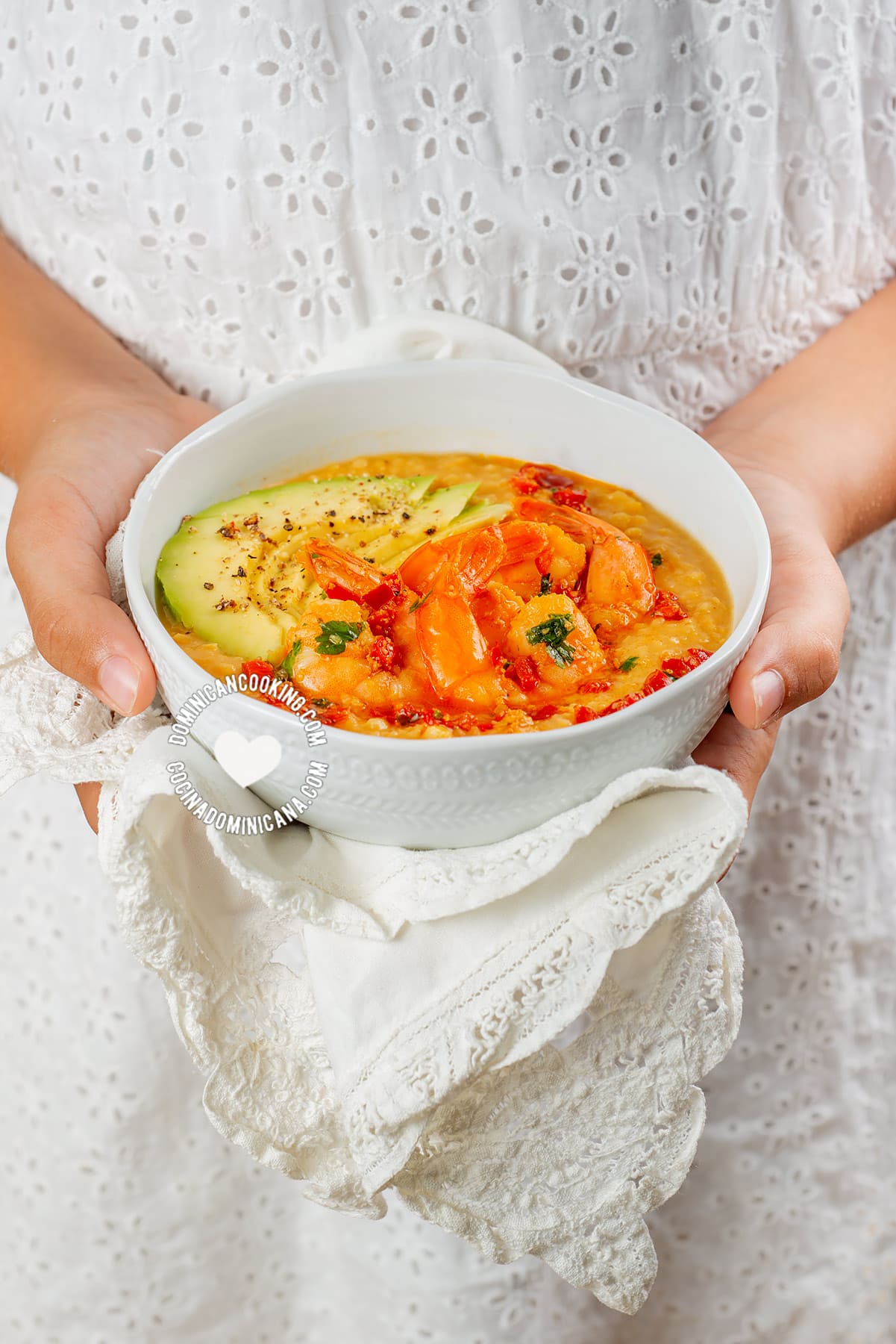 hands holding bowl of spicy sauteed shrimp