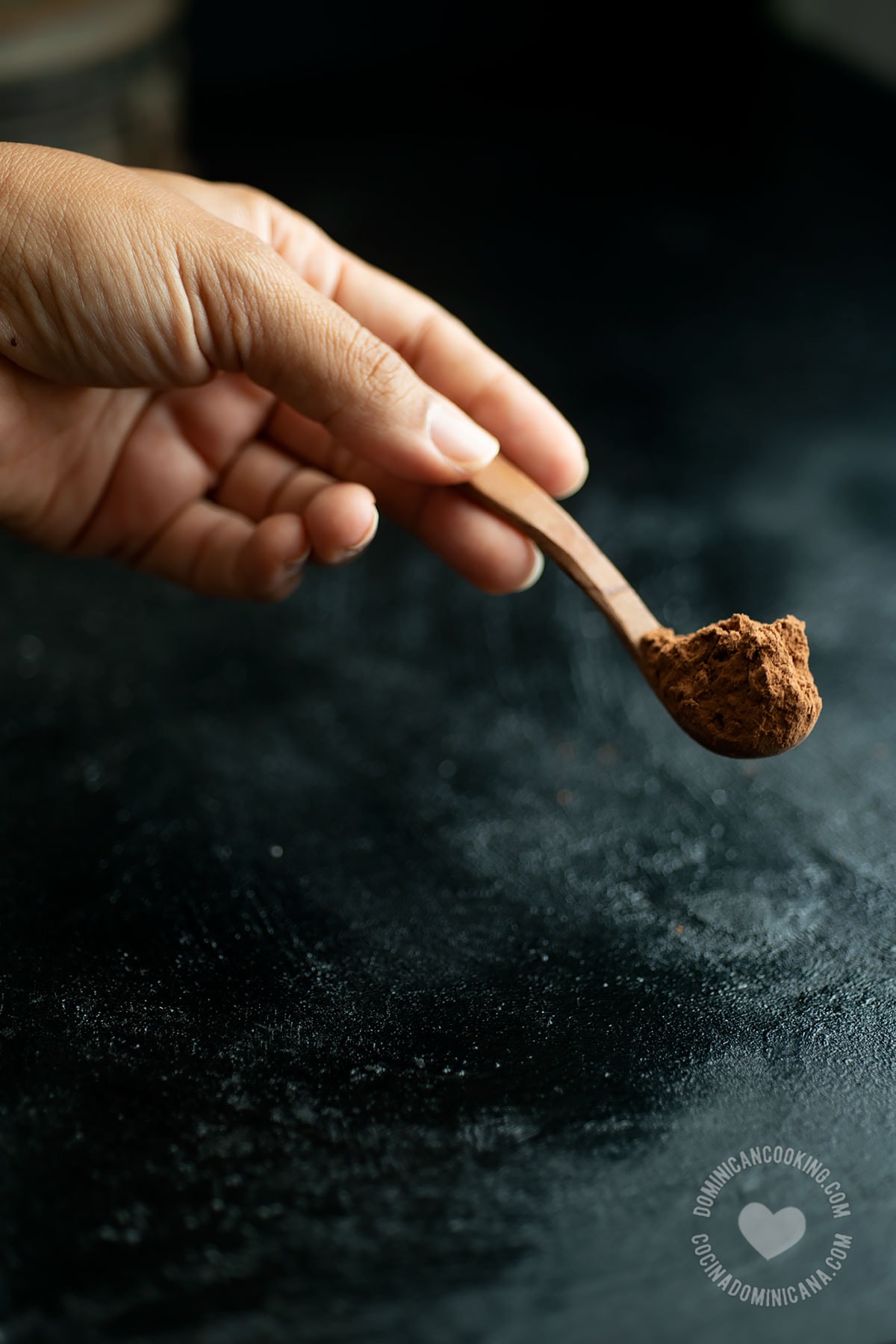 Hand holding spoonful of cocoa powder