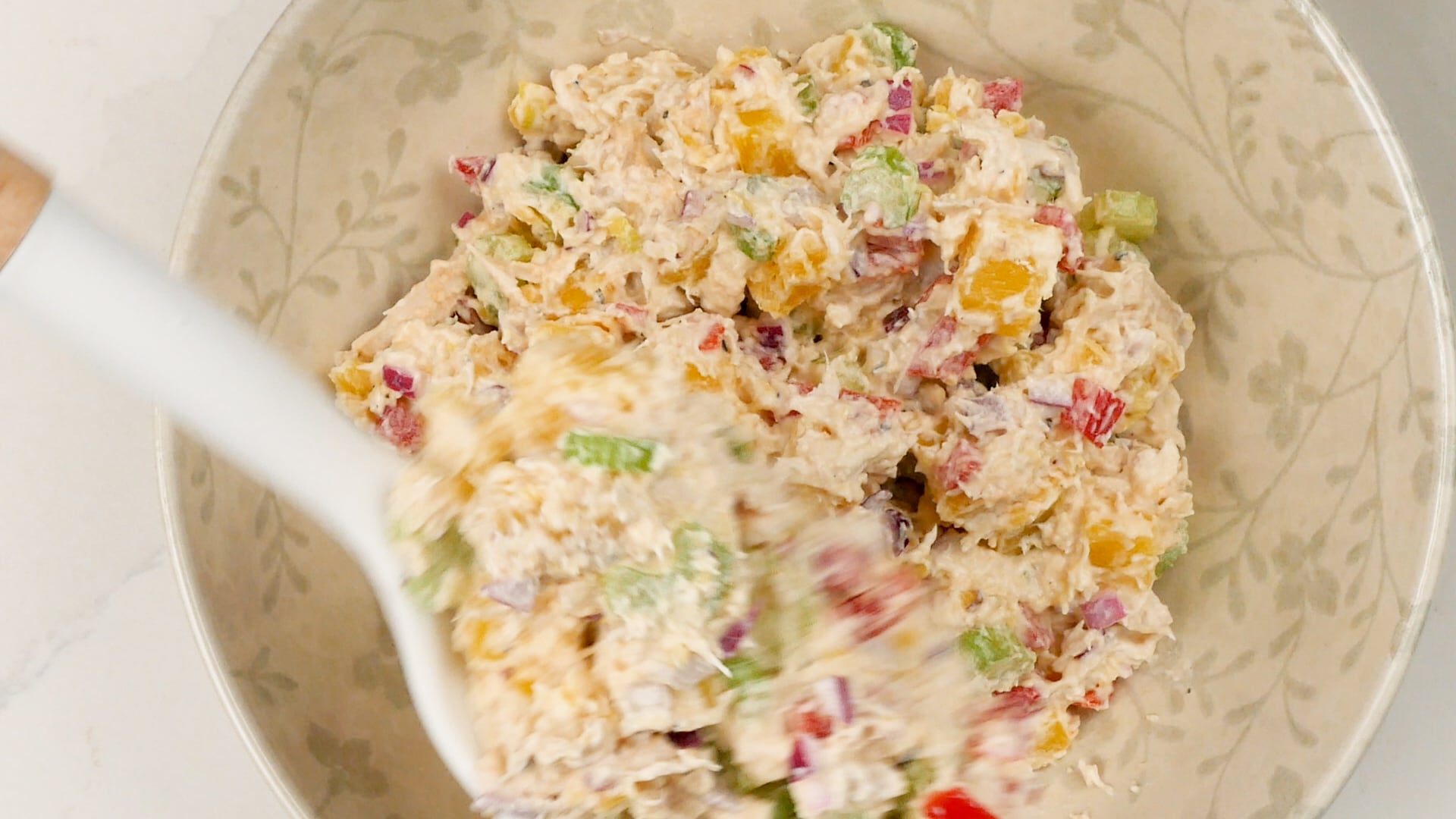 Scooping potato and chicken salad onto a plate