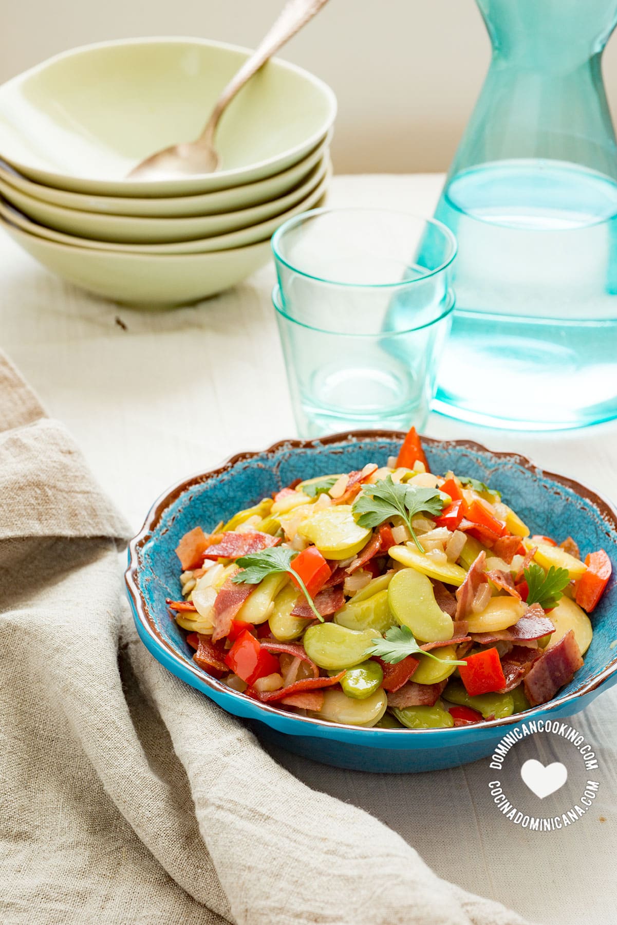 Fava bean and bacon salad with empty bowls in the background