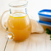 Jar and cups of homemade chicken broth