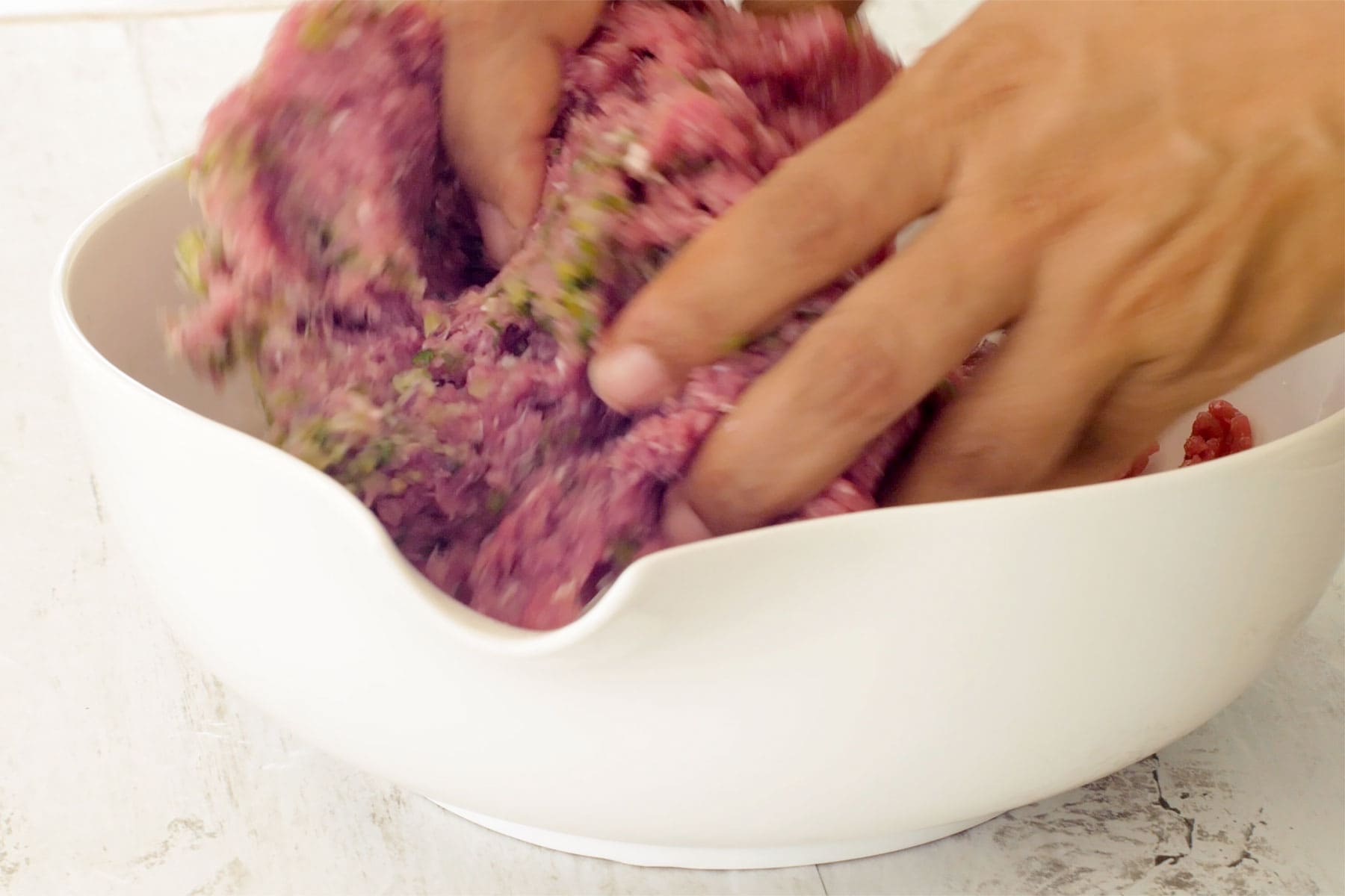 Mixing meat and seasoning with hands