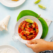 Lambí guisado (caribbean conch stew) served with rice and tostones, hand holding plate