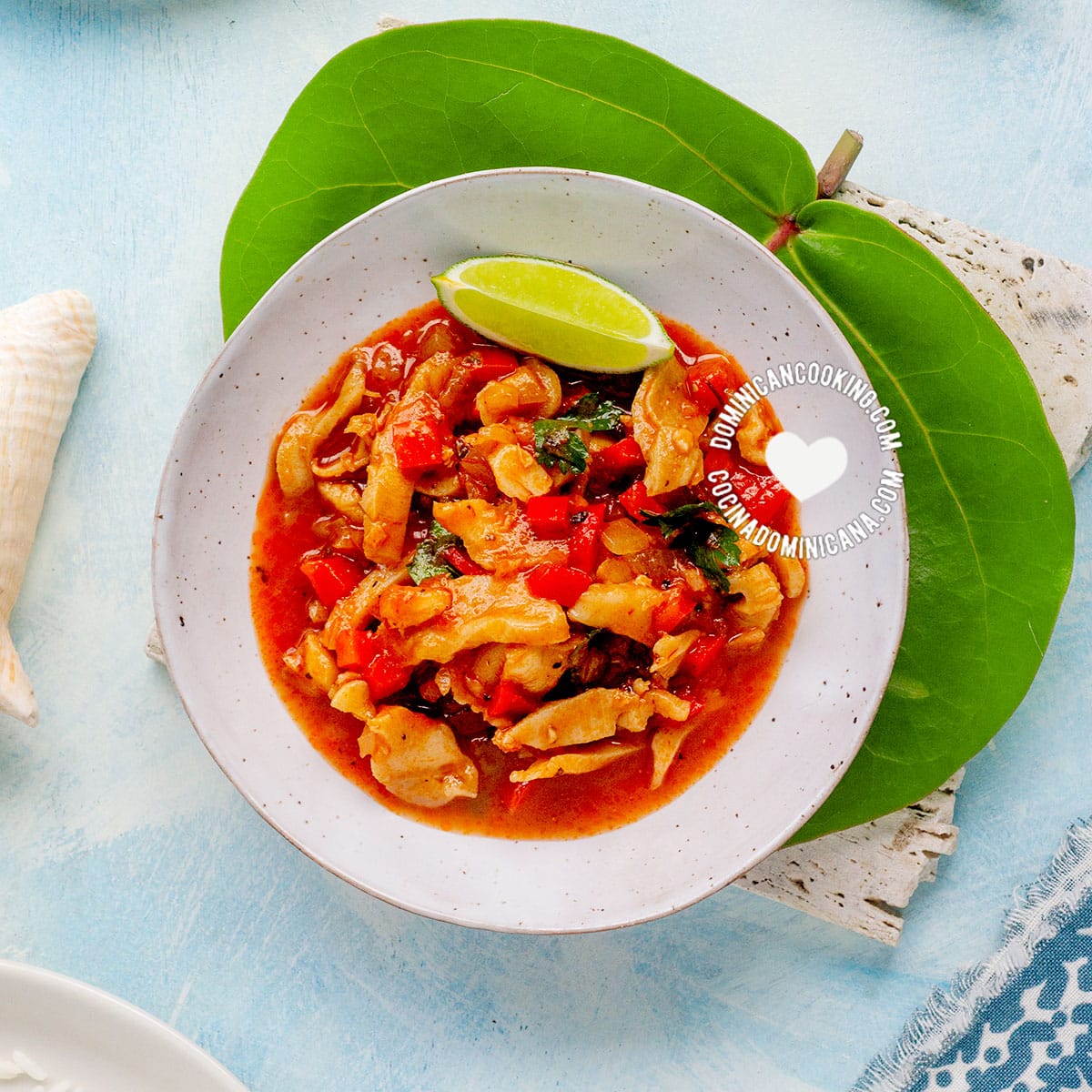 Lambí guisado (caribbean conch stew) served with rice and tostones, plate on cocoloba leaf