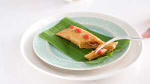 Pastel en hoja served with hot sauce