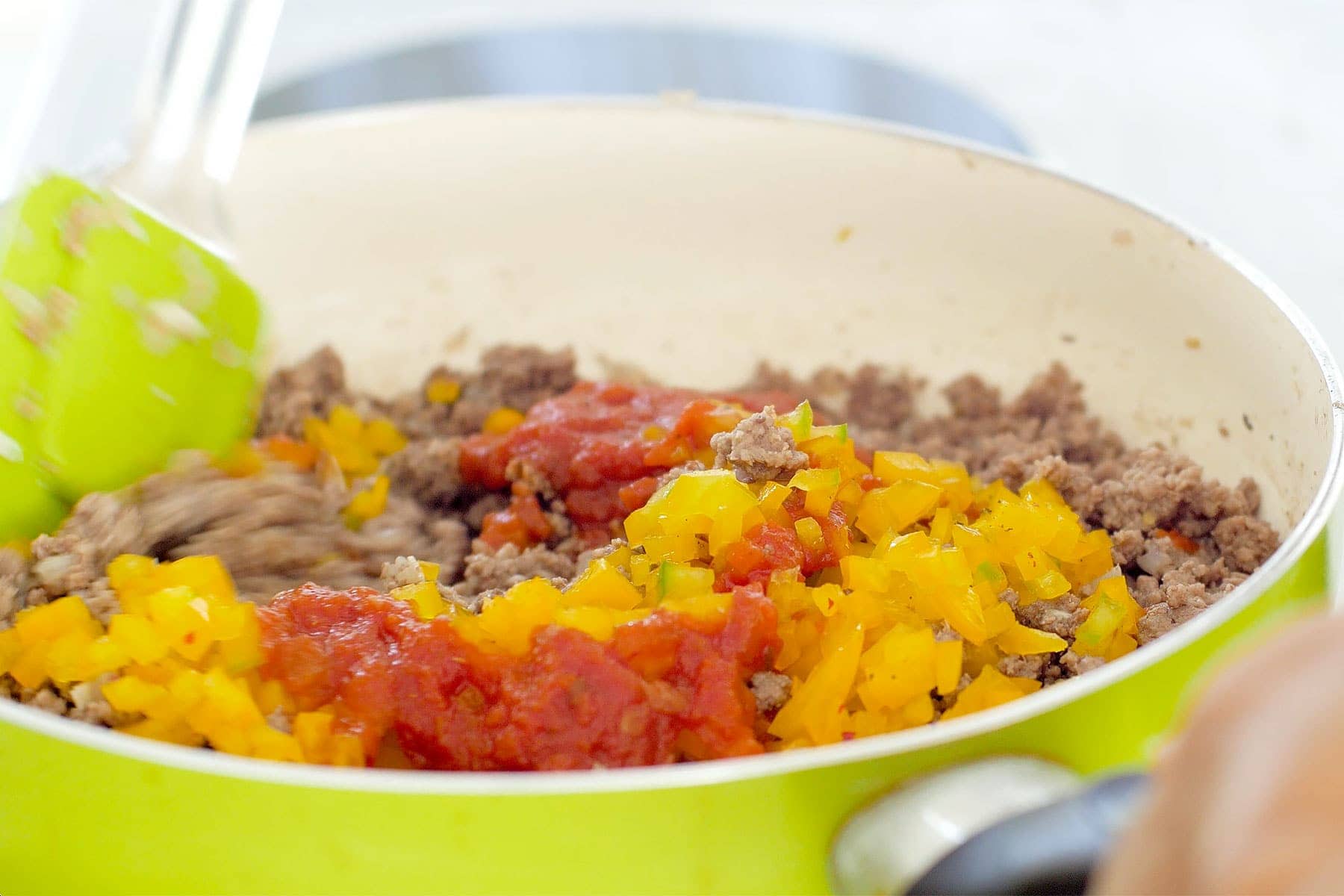 Mixing in pepper and tomato sauce with the meat