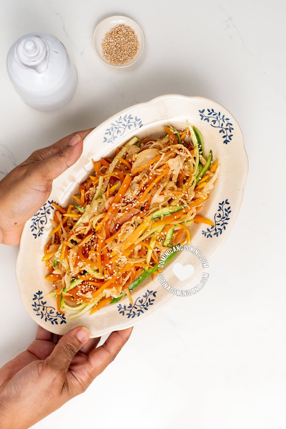 Hands holding plate with green papaya salad