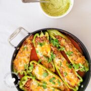 Pan with pepper boats on tomato sauce and bowl with avocado sauce