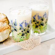 Champola de guanábana in two glasses, plus fruit.