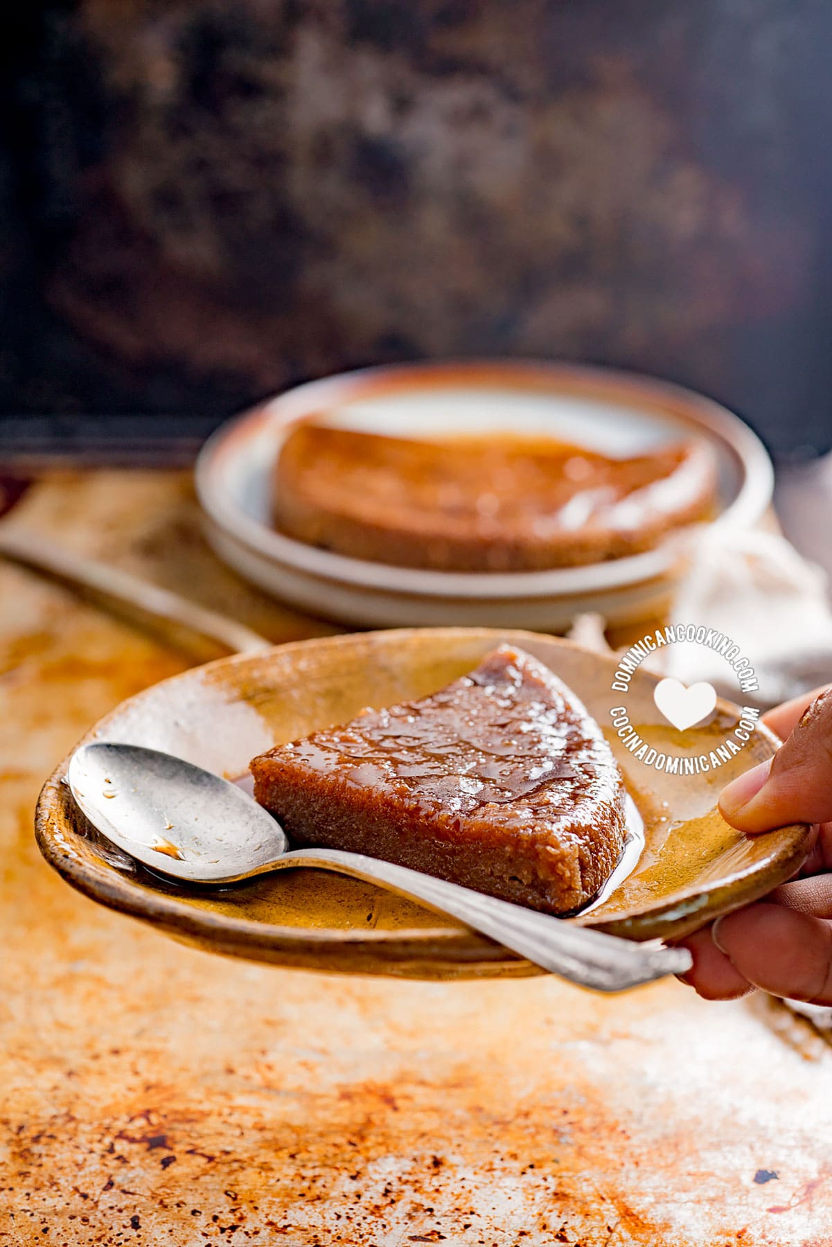 Hand holding a Slice of Cassava Flour (Tapioca) Pudding, More in the Background